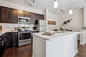 A modern kitchen with a white island and dark brown cabinets.
